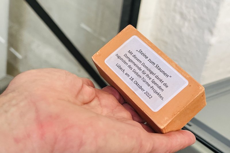 Ein besonderer Domziegel in Kleinformat mit der Aufschrift "Steine zum Staunen" Mit diesem Domziegel dankt die Domgemeinde für Ihre Spenden zugunsten des Sieben-Türme-Projektes. Lübeck, am 18. Oktober 2022