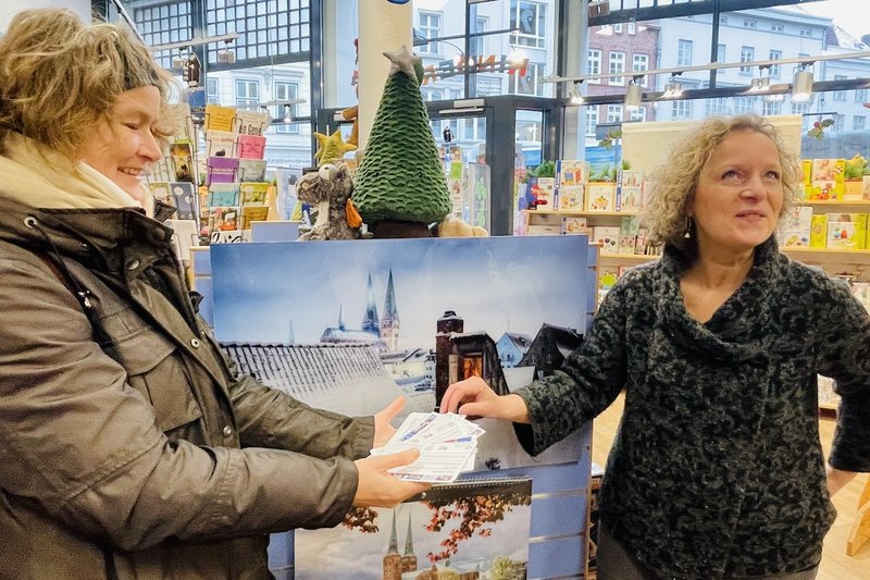 Im Geschäft "Kinderkream" hält Heike Reimann (li) die Verlosungskarten und Frau Ernst zieht daraus eine Gewinnerkarte.