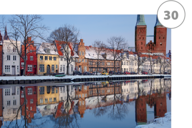 Blick über die Häuser an der Obertrave zum Lübecker Dom |Der Dom und die Altstadthäuser spiegeln sich mit leicht schneebedeckten Dächern in der ruhigen Wasseroberfläche
