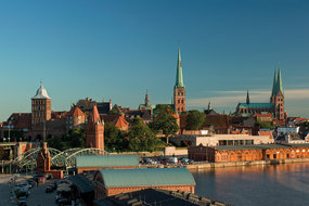 Im Vordergrund sieht man die Mediadocks und die Hubbrücke von Lübeck. Im Hintergrund ist das Burgtor auf der linken Seite zu sehen, rechts daneben St. Jakobi und St. Marien.