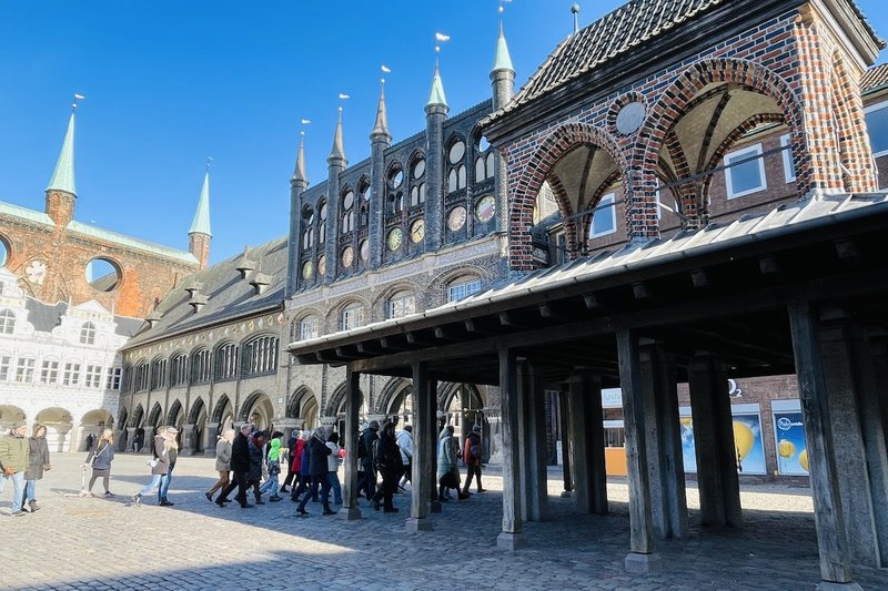 Der Pranger (Kaak) auf dem Rathausmarkt Lübeck, blauer Himmel und gehende Menschen