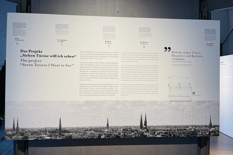 Eine Tafel mit einem Panoramabild der Sieben-Türme Lübeck und Texte zu den einzelnen Kirchen.
