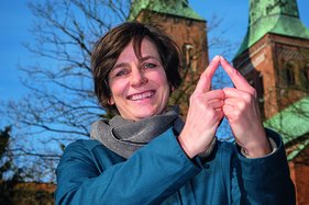 Christine Koretzky - Welterbebeauftragte der Hansestadt Lübeck zeigt das Sieben-Türme-Symbol mit ihren Zeigefingern