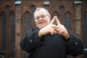 Der ehemalige Schirmherr Lienhard Böhning zeigt mit seinen beiden Zeigefingern das Sieben-Türme-Symbol