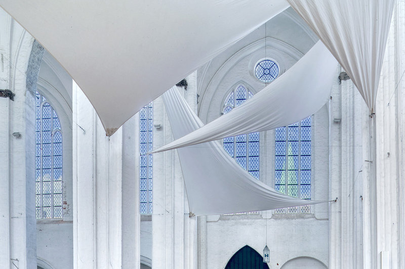 Weiße Segel sind im Inneren von St. Petri gespannt und die weißen Säulen geben einen wunderschönen Kontrast zu den Kirchenfenstern im Hintergrund. Der Himmel leuchtet im schönen blau und  St. Marien ist durch das rechte Fenster zu sehen.
