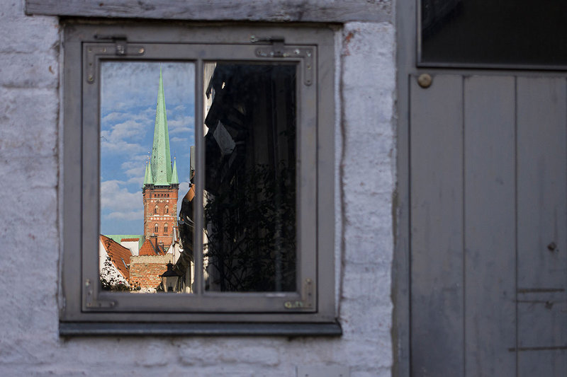 Durch ein Fenster sieht man den St.-Petri-Turm